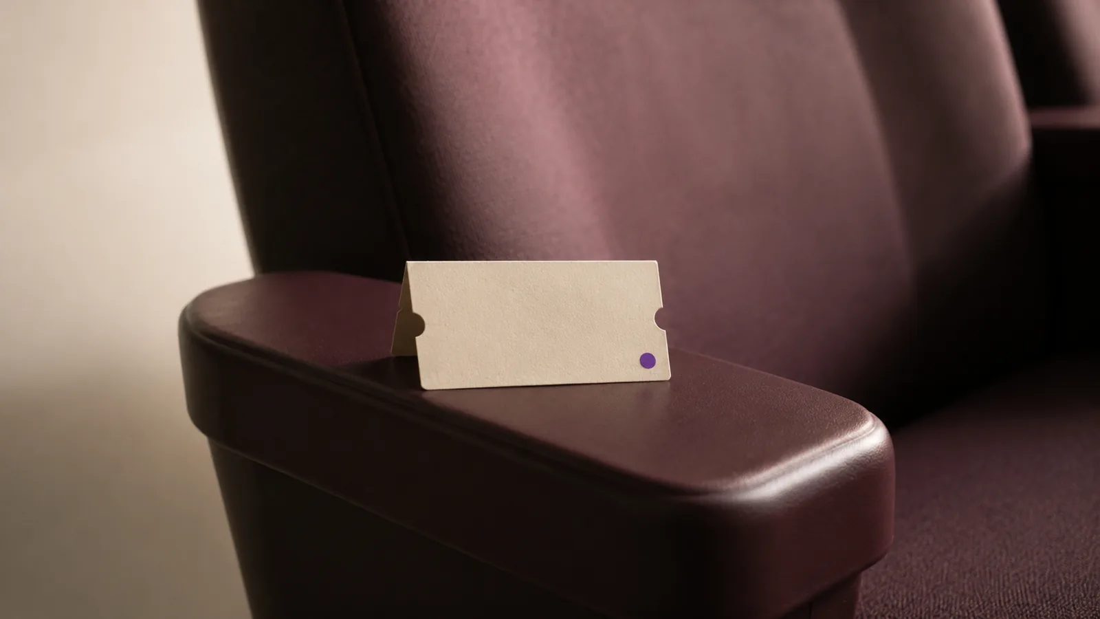 A folded cinema ticket stub on the arm of an empty seat.