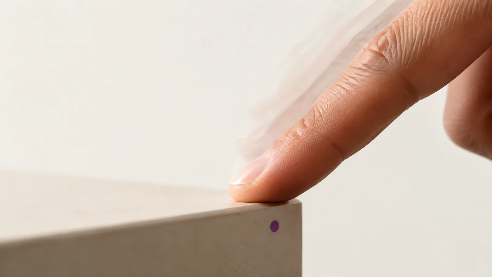 A finger tapping the edge of a table, cropped closely.