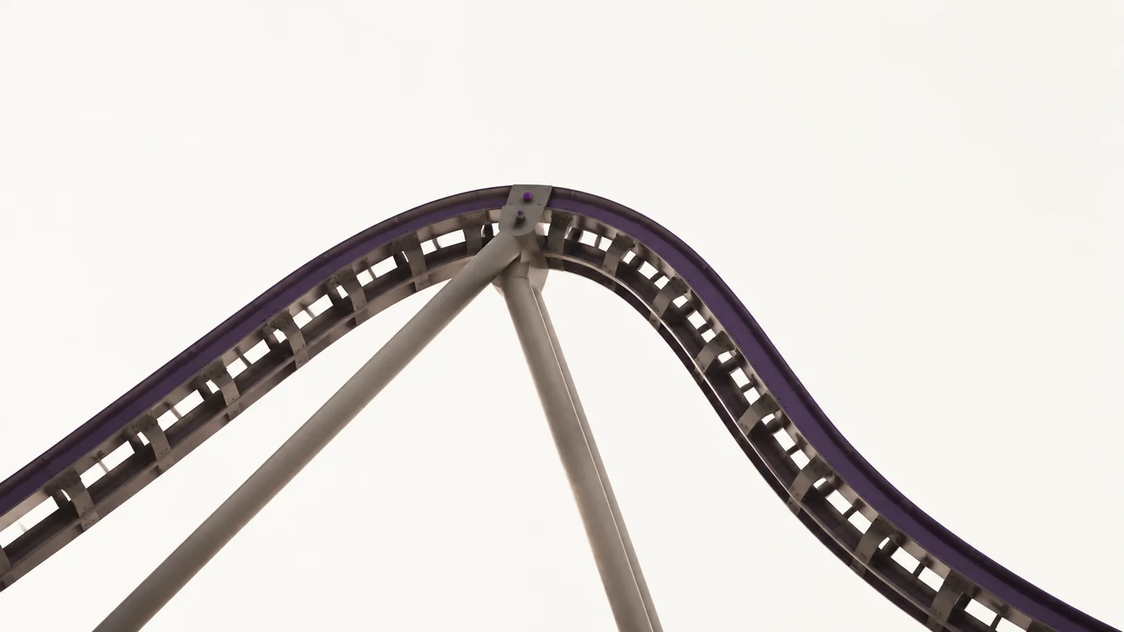 A rollercoaster track against a plain sky, only the crest and descent visible.